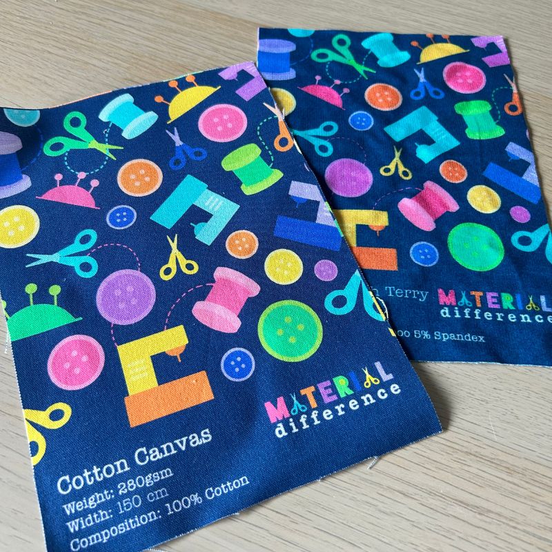 Two pieces of fabric with sewing-themed patterns on a wooden surface