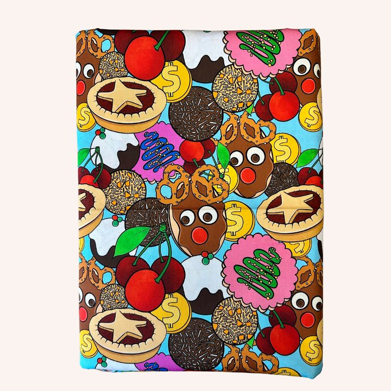 Cotton fabric featuring a colorful cartoon pattern of Christmas treats, pretzels, pies, cherries, and reindeer on a light blue background.
